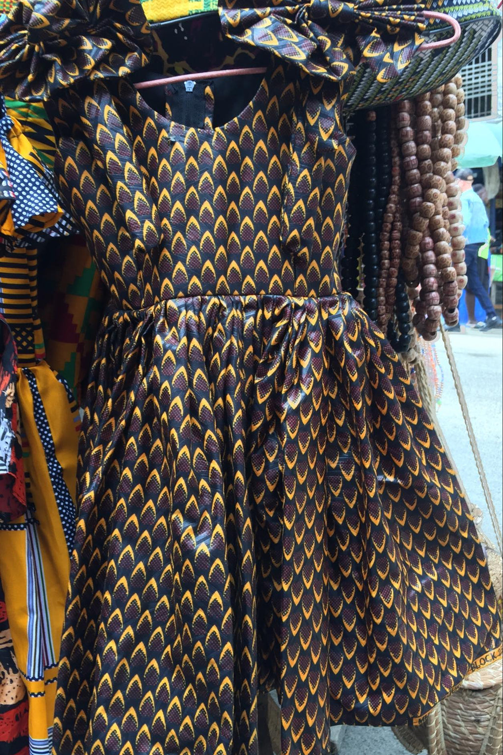 Traditional African print dress on a mannequin with beads in the background