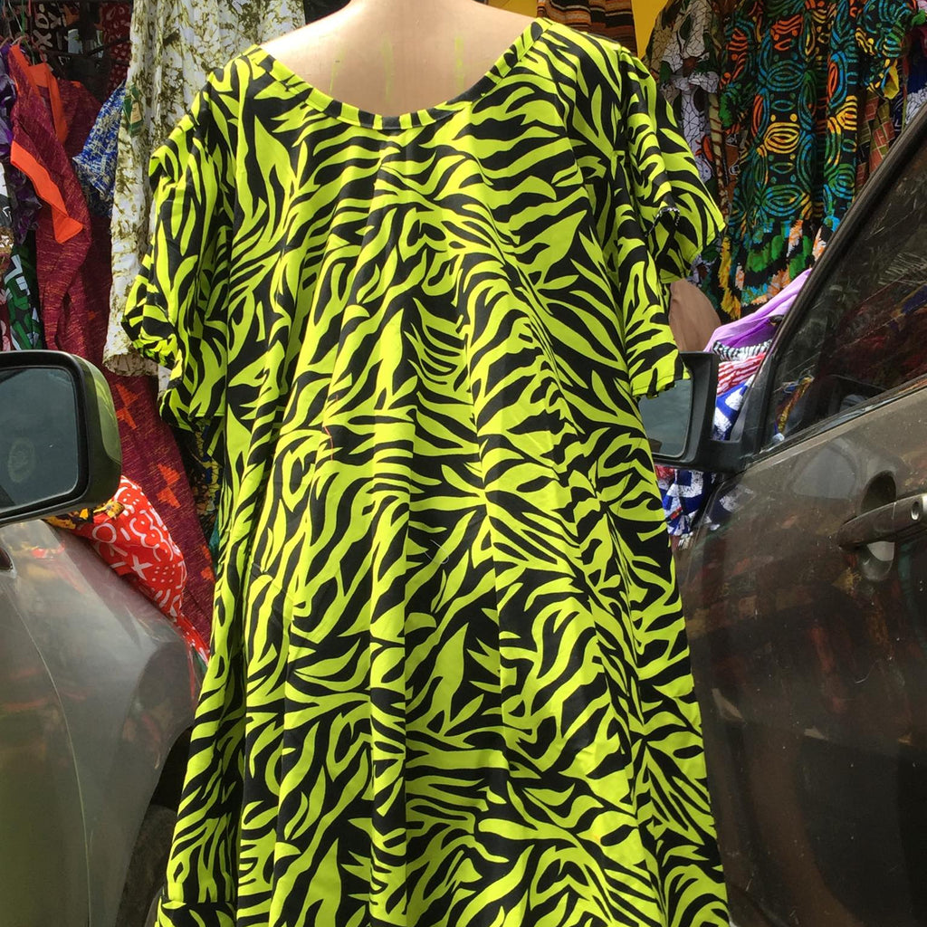 Mannequin wearing a bright yellow and black zebra pattern dress in an outdoor market setting.