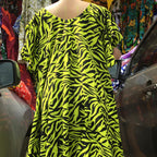 Mannequin wearing a bright yellow and black zebra pattern dress in an outdoor market setting.