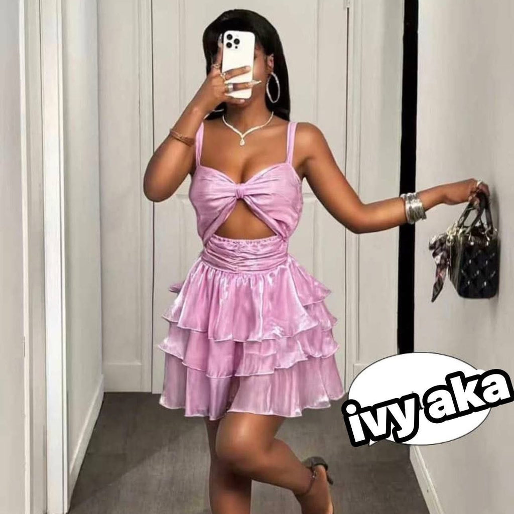 Person wearing a pink dress taking a mirror selfie in a hallway.