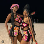 Two women wearing colorful crochet outfits on a beach.