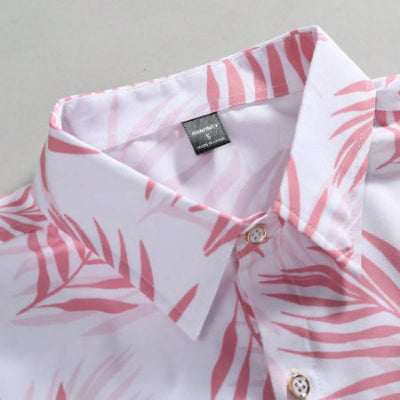 A close-up of a white button-down shirt with a pink palm leaf pattern, showing the collar, buttons, and a brand label that reads 'SANDMATS'.