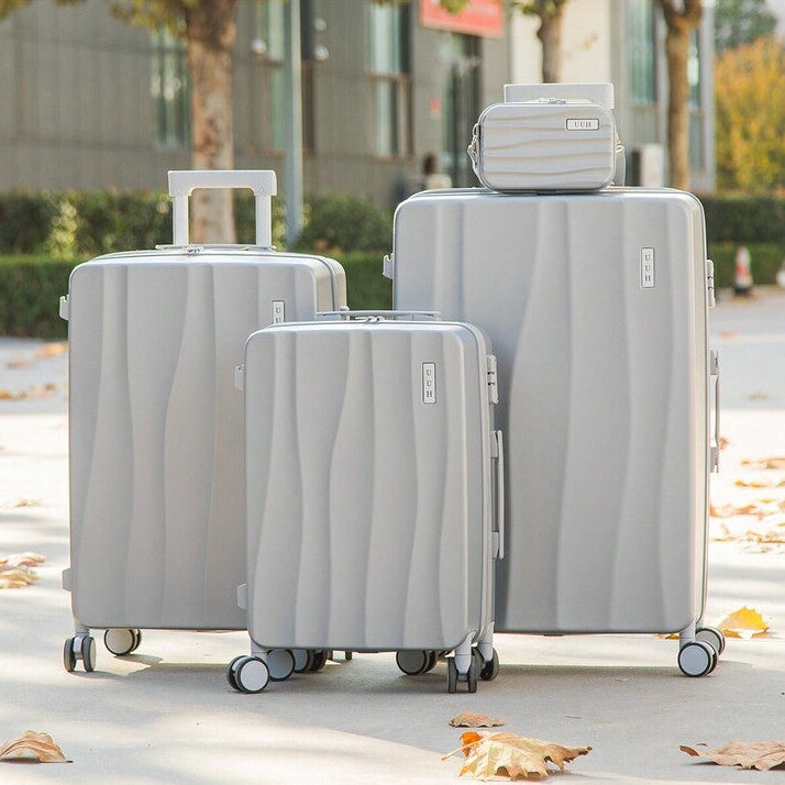 Set of gray suitcases with a matching travel bag on a sidewalk.