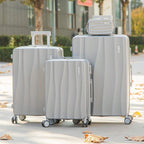 Set of gray suitcases with a matching travel bag on a sidewalk.