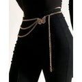 Gold chain belt with a butterfly design on a black outfit against a white background