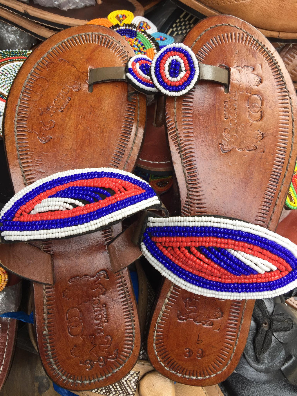 Pair of brown leather sandals with colorful beaded straps on a blurred background