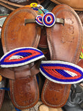 Pair of brown leather sandals with colorful beaded straps on a blurred background