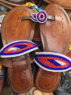 Pair of brown leather sandals with colorful beaded straps on a blurred background