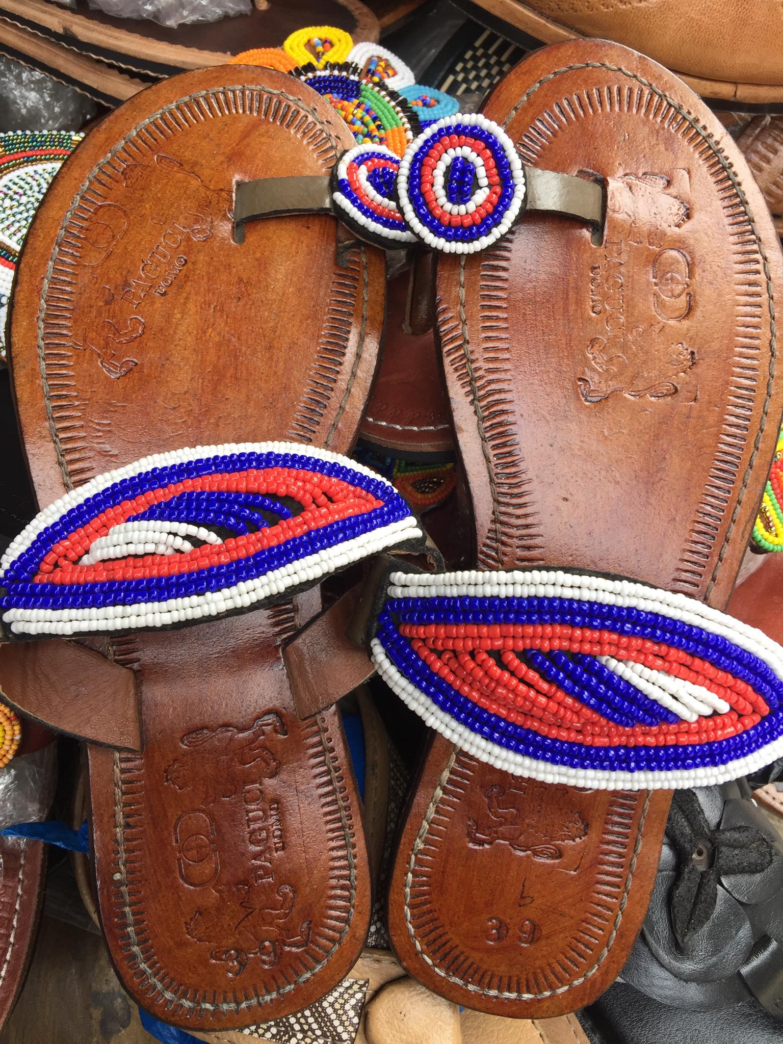 Pair of brown leather sandals with colorful beaded straps on a blurred background