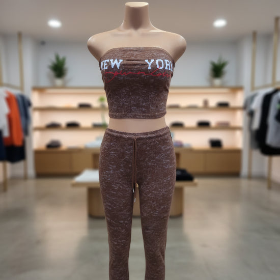 A mannequin or torso form wearing a brown marled ribbed tube top and matching leggings. The tube top has large white 'NEW YORK' lettering and a red script line across the chest.