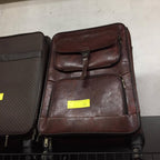 Brown leather suitcase with a yellow tag on a metal surface