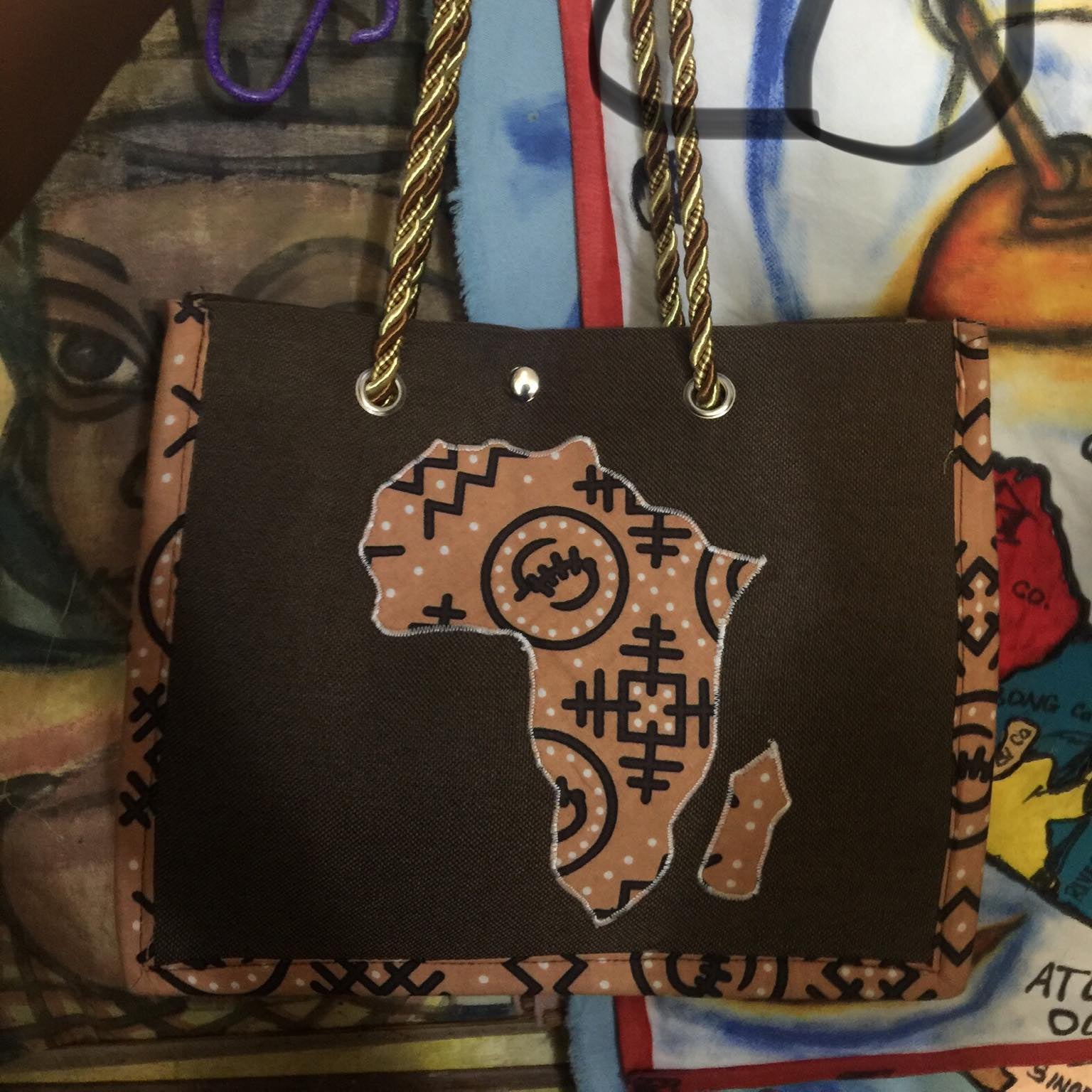 Brown bag with Africa map design held by a hand against a colorful background