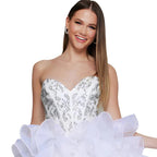 Woman wearing a white strapless dress with sequin bodice and ruffled skirt on a white background