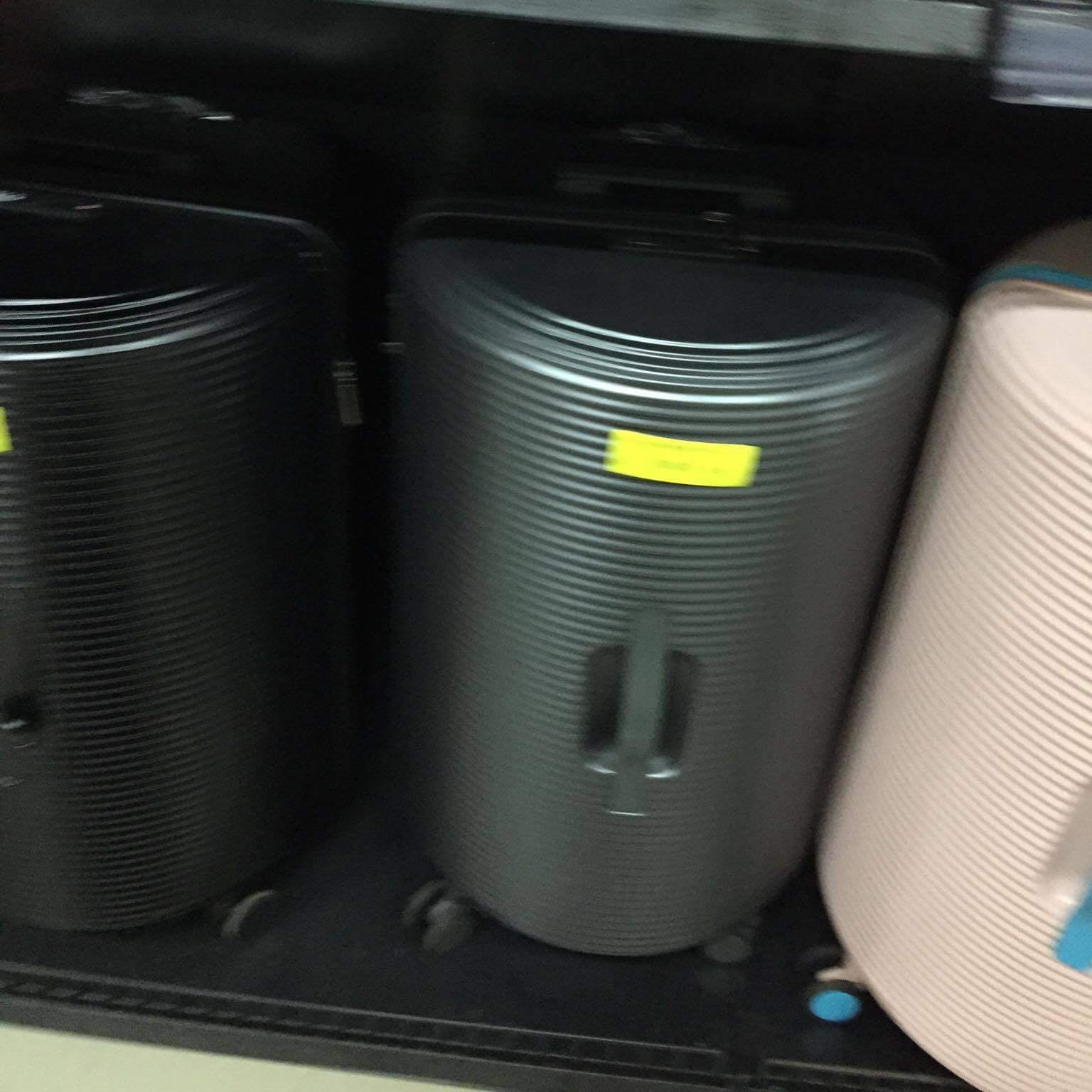 Two black suitcases with yellow labels inside a store
