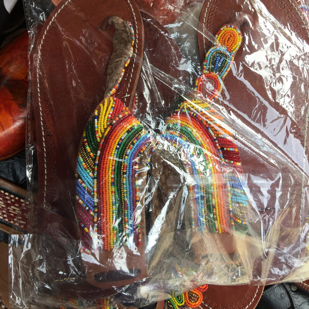 Colorful beaded rainbow keychain in clear packaging with brown leather background