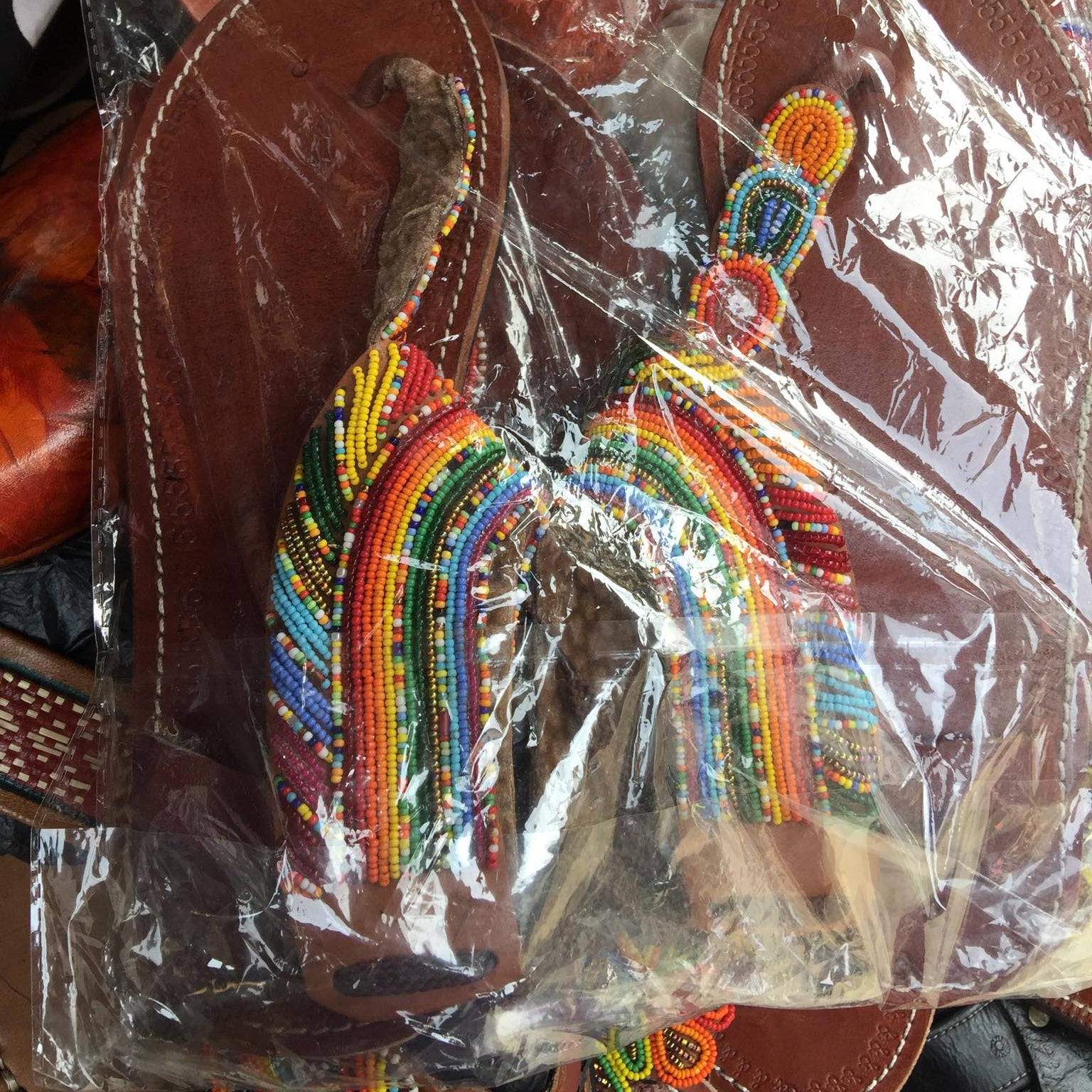 Colorful beaded rainbow keychain in clear packaging with brown leather background