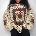 Person wearing a crocheted sweater with a pattern against a plain background