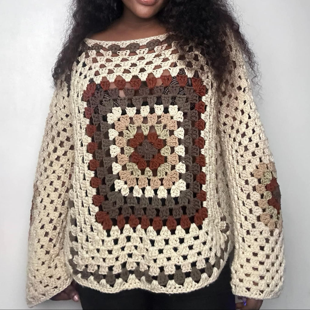 Woman wearing a crocheted sweater with a pattern on a plain background