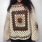 Woman wearing a crocheted sweater with a pattern on a plain background