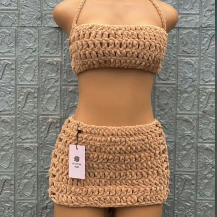 Crocheted beige bikini set on a mannequin against a textured gray wall.