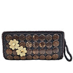 Woven clutch with circular patterns and floral embellishments on a white background