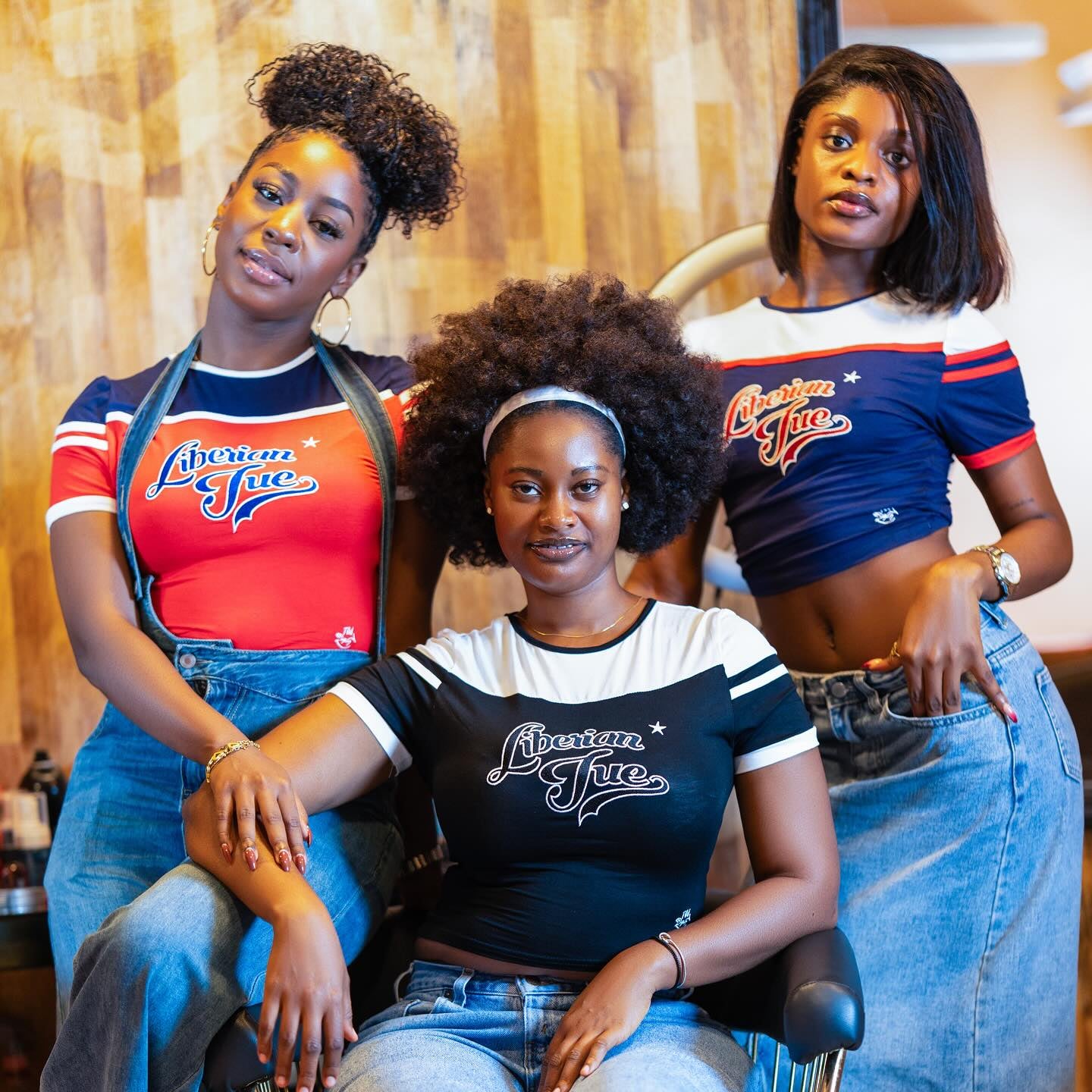 Three women wearing 'American Free' t-shirts and denim skirts in a casual setting.