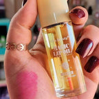 Hand holding a bottle of Kiss Beauty Magic Lip Oil with a blurred background