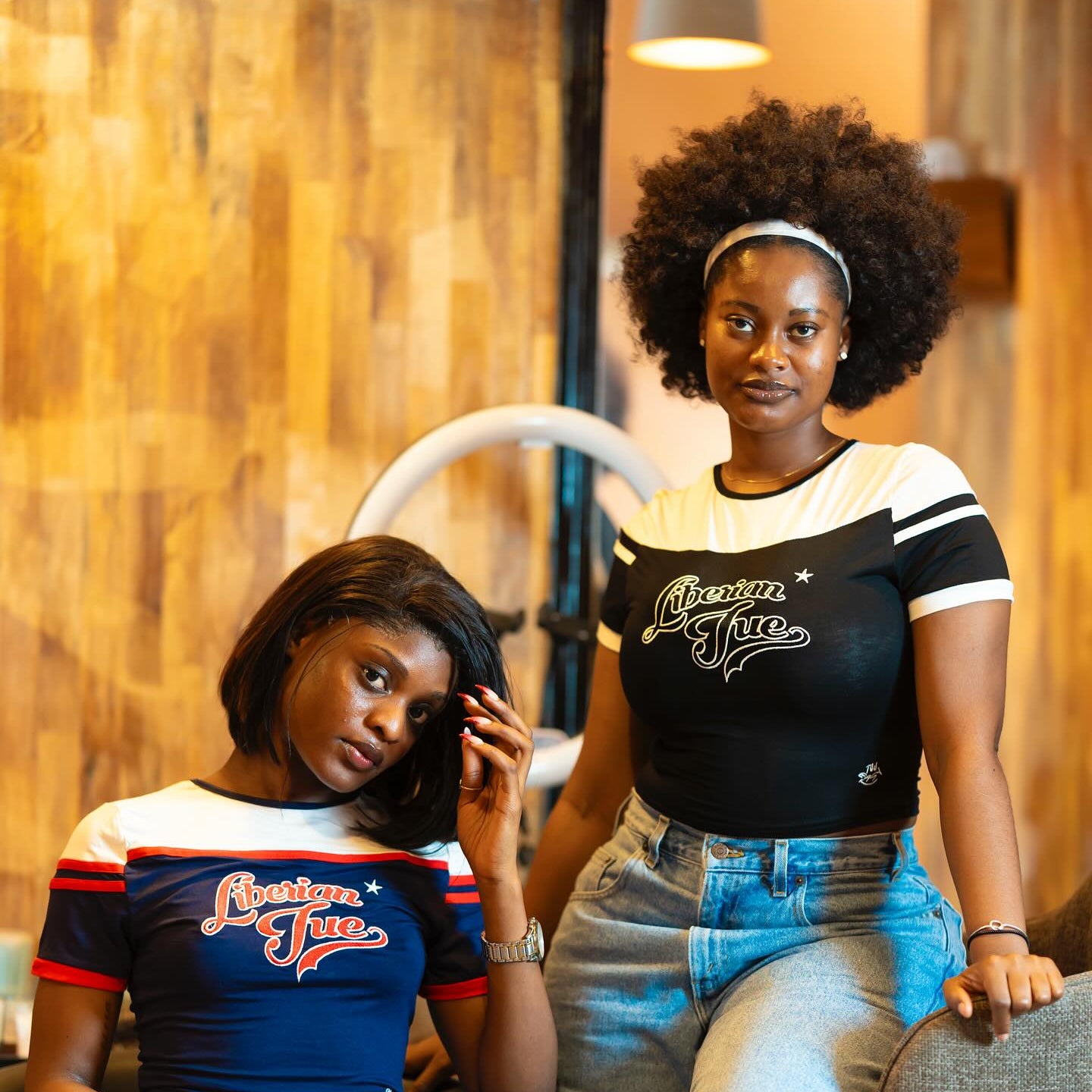 Two women sitting on chairs in a room with wooden walls.
