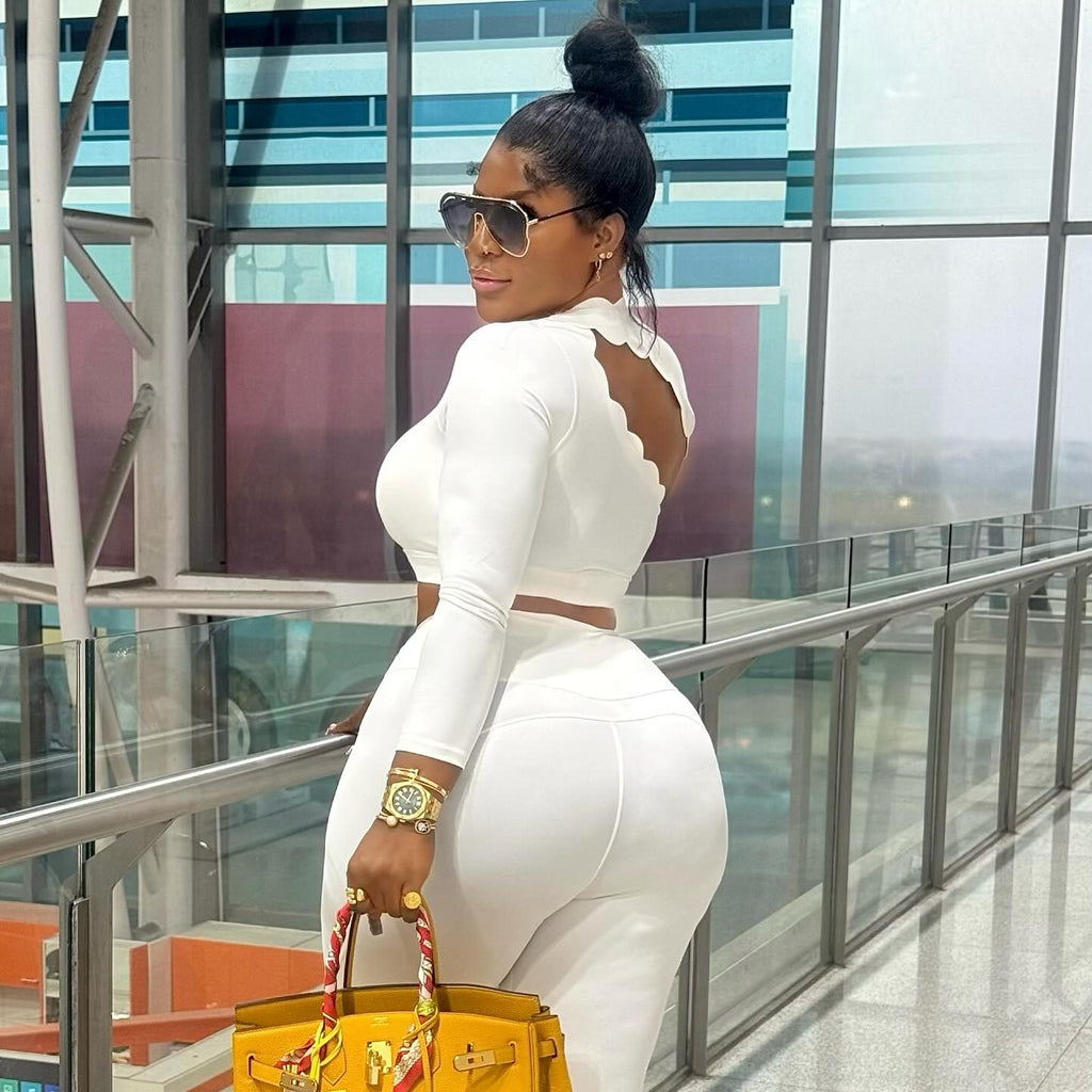 Woman in a white outfit holding a yellow handbag in an indoor setting