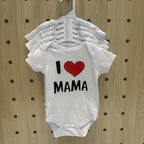 White baby onesie with 'I ❤️ MAMA' text on a wooden pegboard background