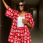 Woman in a red and white patterned outfit holding a drink in a hallway.