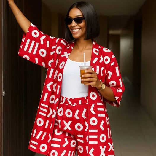 Woman in a red and white patterned outfit holding a drink in a hallway.
