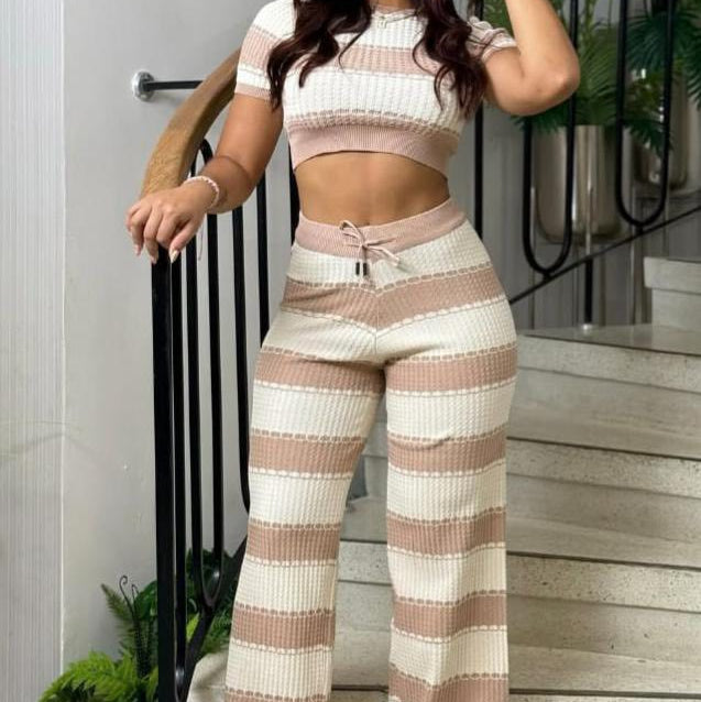 Woman wearing a striped outfit standing on a staircase with plants in the background