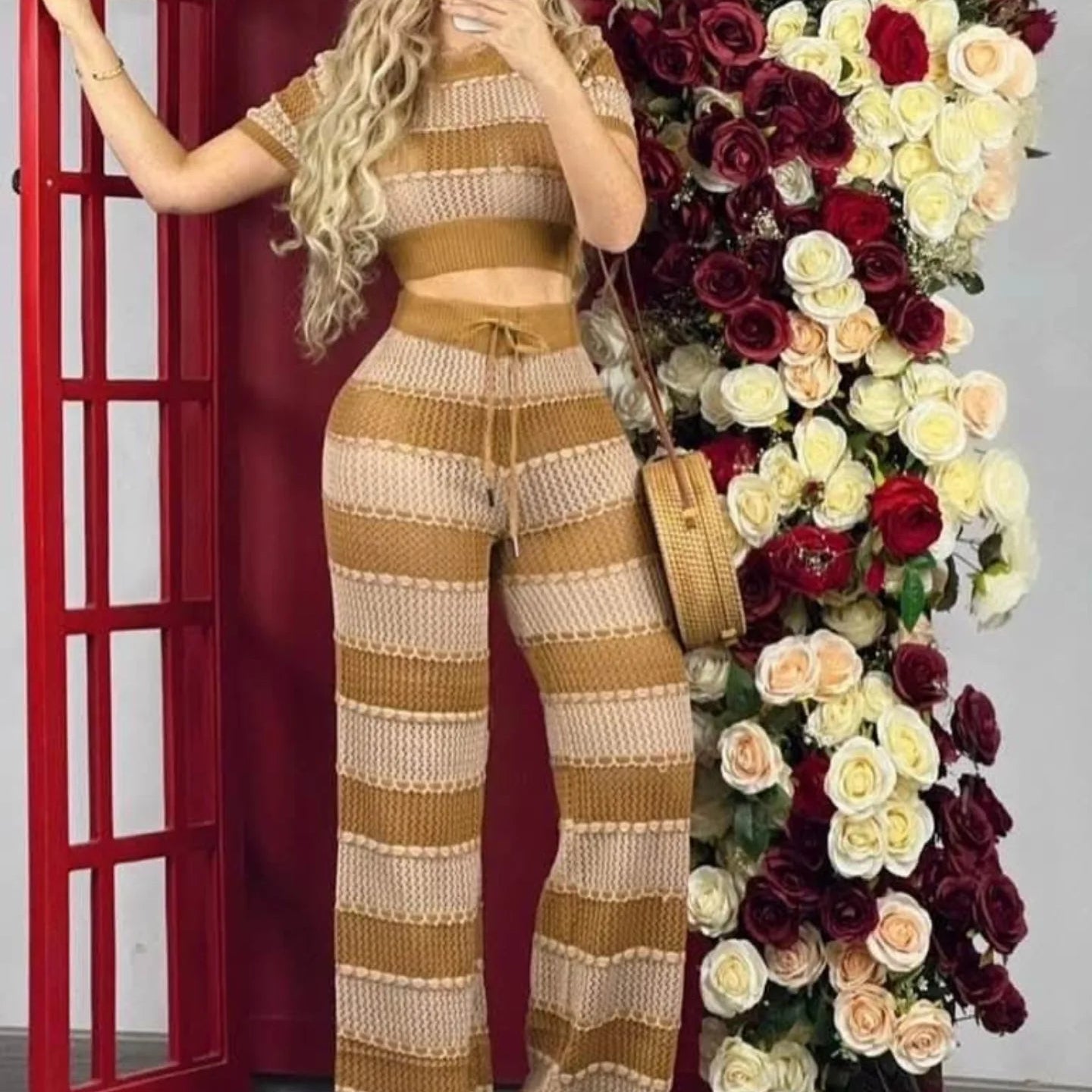 Person wearing a striped outfit standing next to a floral arrangement.