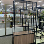 Room divider with glass panels and wooden base in a store setting