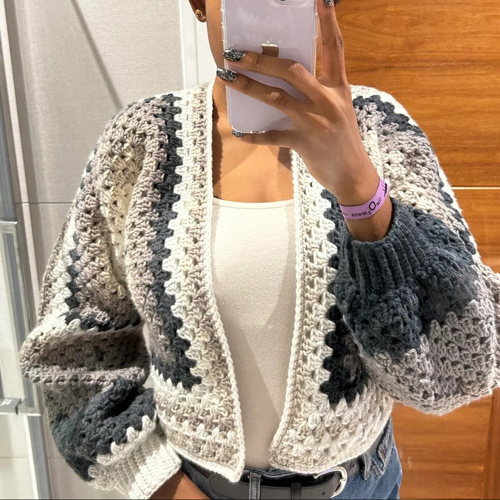 Person wearing a gray and white crochet cardigan taking a mirror selfie.