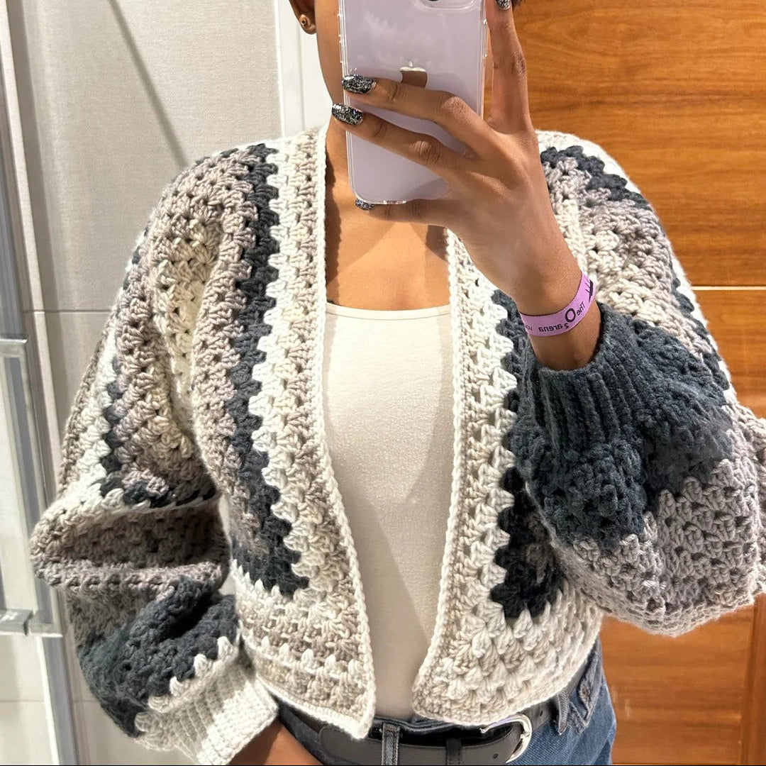 Person wearing a gray and white crochet cardigan taking a mirror selfie.