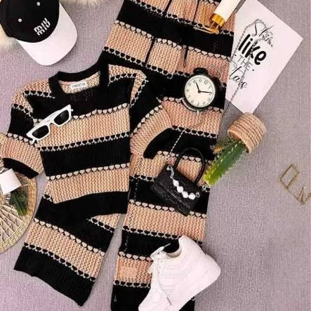 Black and beige striped sweater and pants set with accessories on a light gray background
