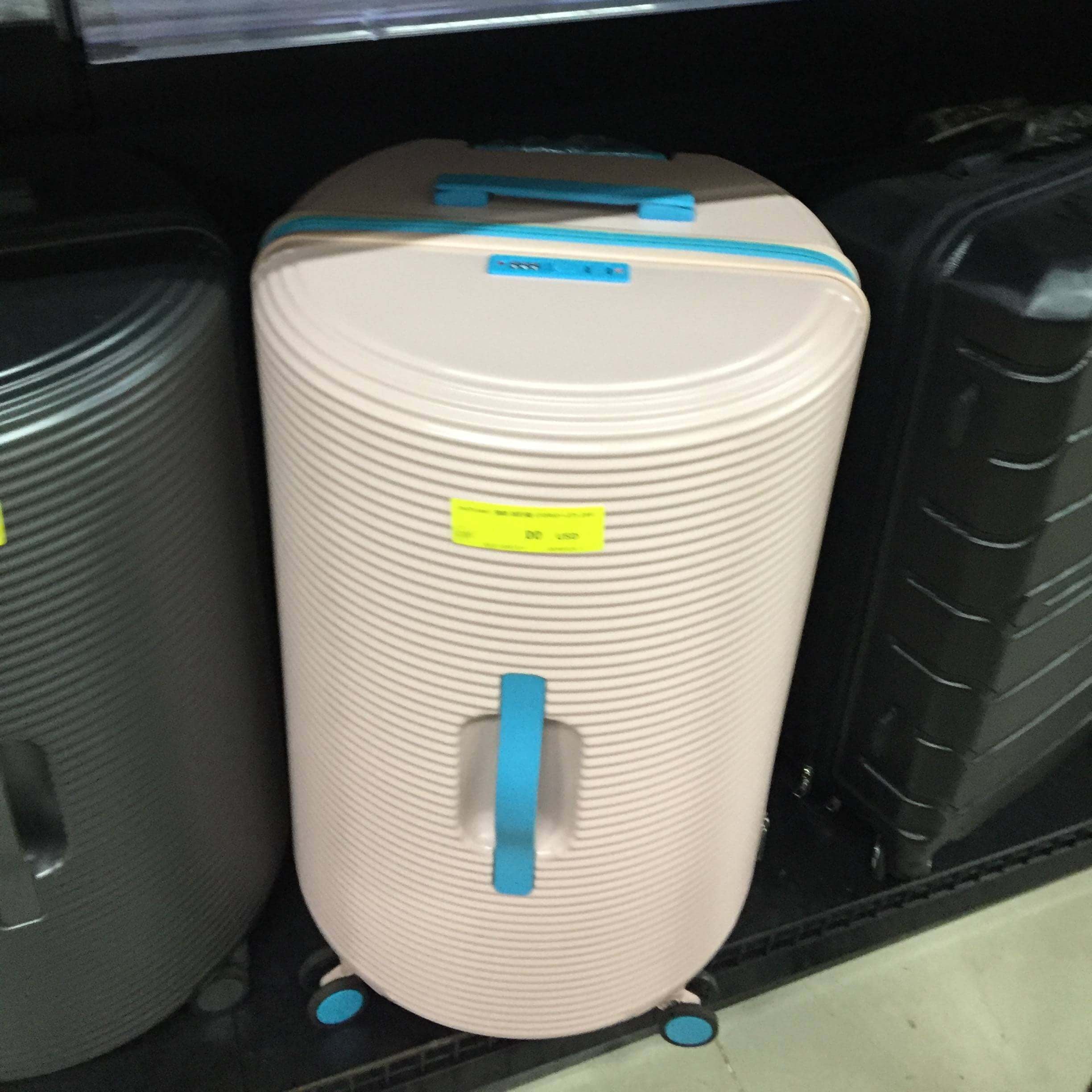 Beige suitcase with blue handles and wheels inside a vehicle.