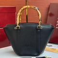 Black handbag with gold handle and Gucci logo on a red box background