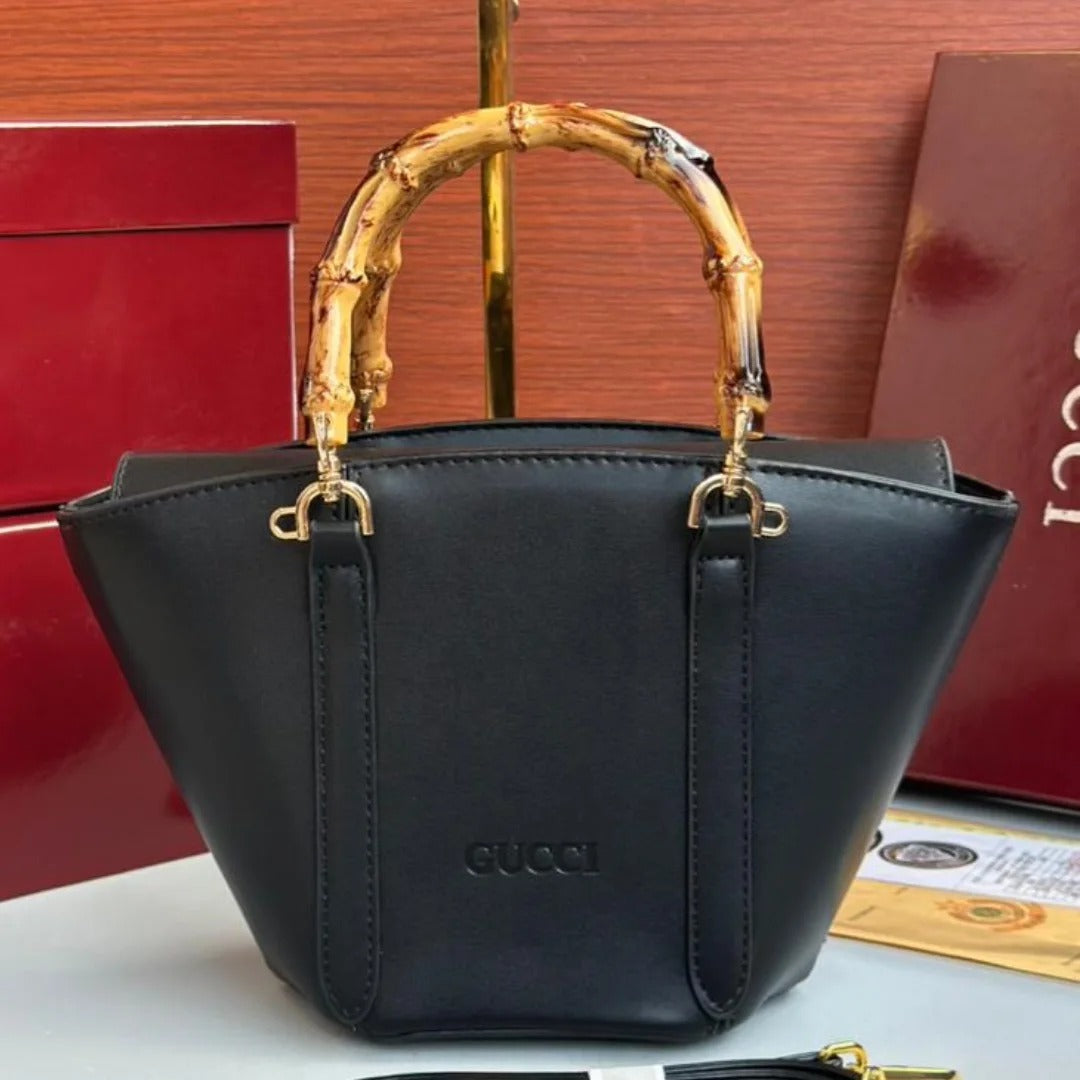 Black handbag with gold handle and Gucci logo on a red box background