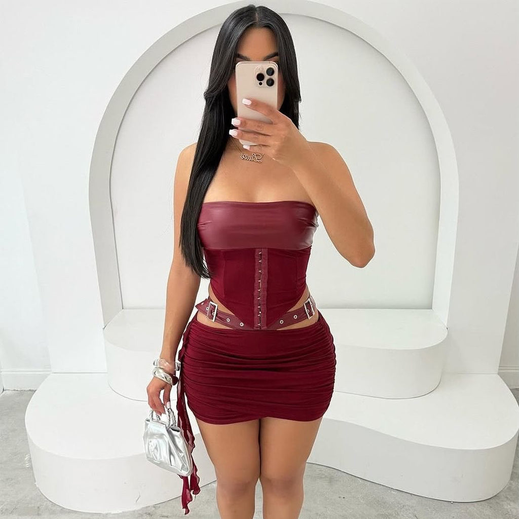 Woman taking a mirror selfie wearing a burgundy strapless dress with a white background