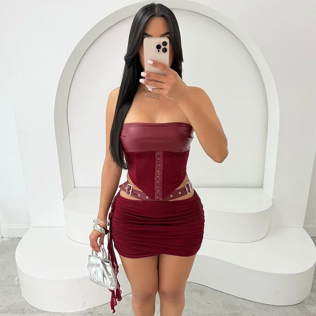 Woman taking a mirror selfie wearing a burgundy strapless dress with a white background