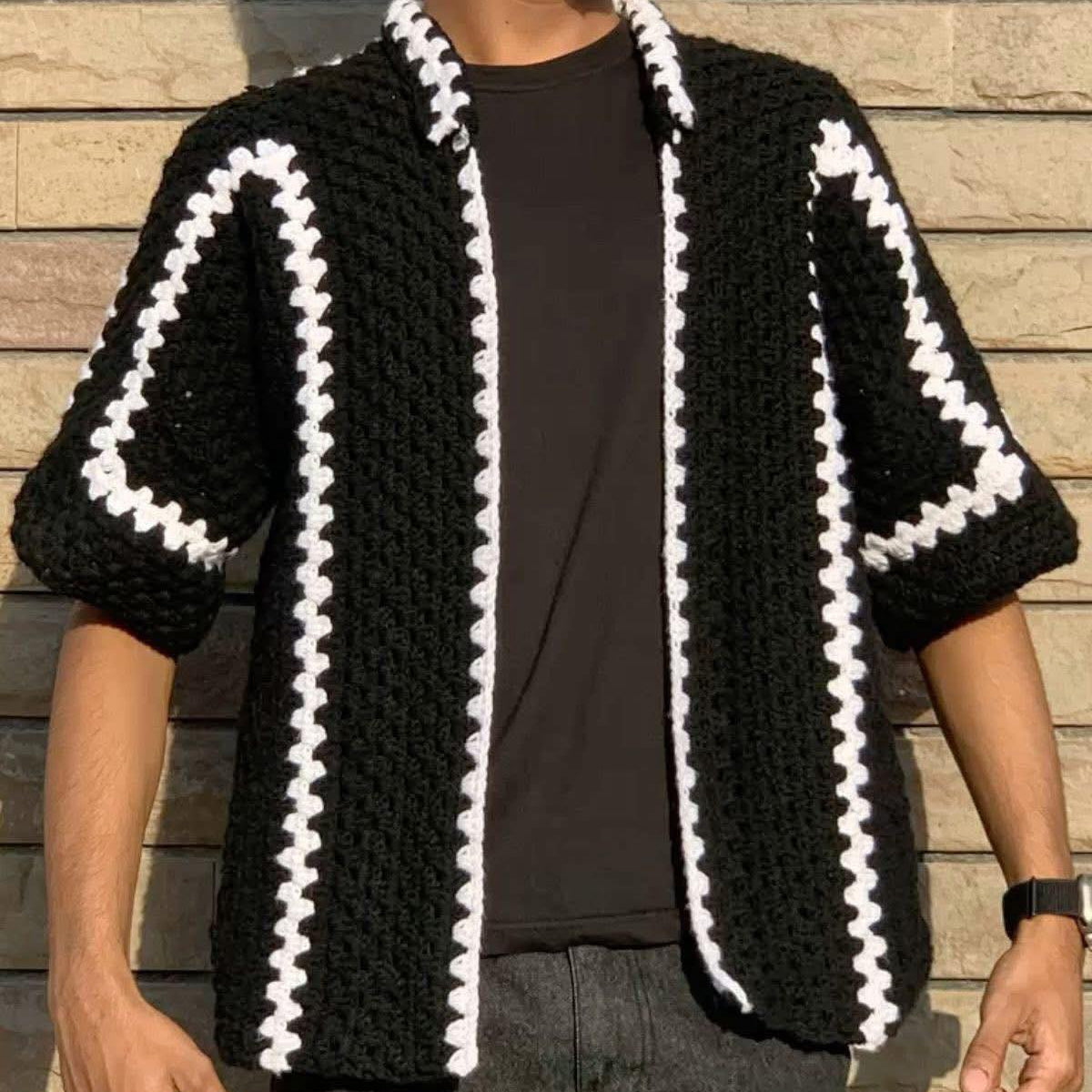 Person wearing a black and white patterned knitted cardigan against a wooden background