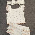Baby romper set with ruffled details and matching headband on a textured surface