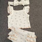 Baby romper set with ruffled details and matching headband on a textured surface