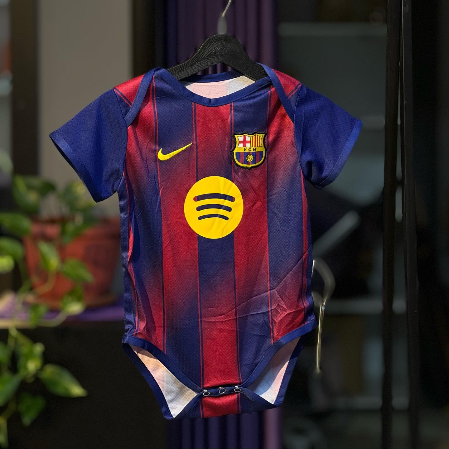 Children's sports jersey with a logo on a hanger against a blurred background