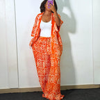 Person wearing an orange and white patterned outfit in front of a white wall with 'Amika' branding.