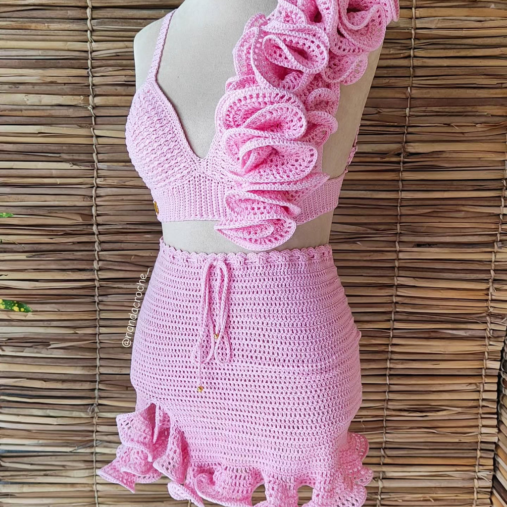Pink crochet dress on a mannequin against a woven background