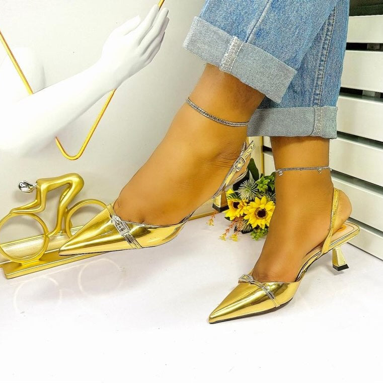Gold high-heeled shoes worn with rolled-up jeans on a white background